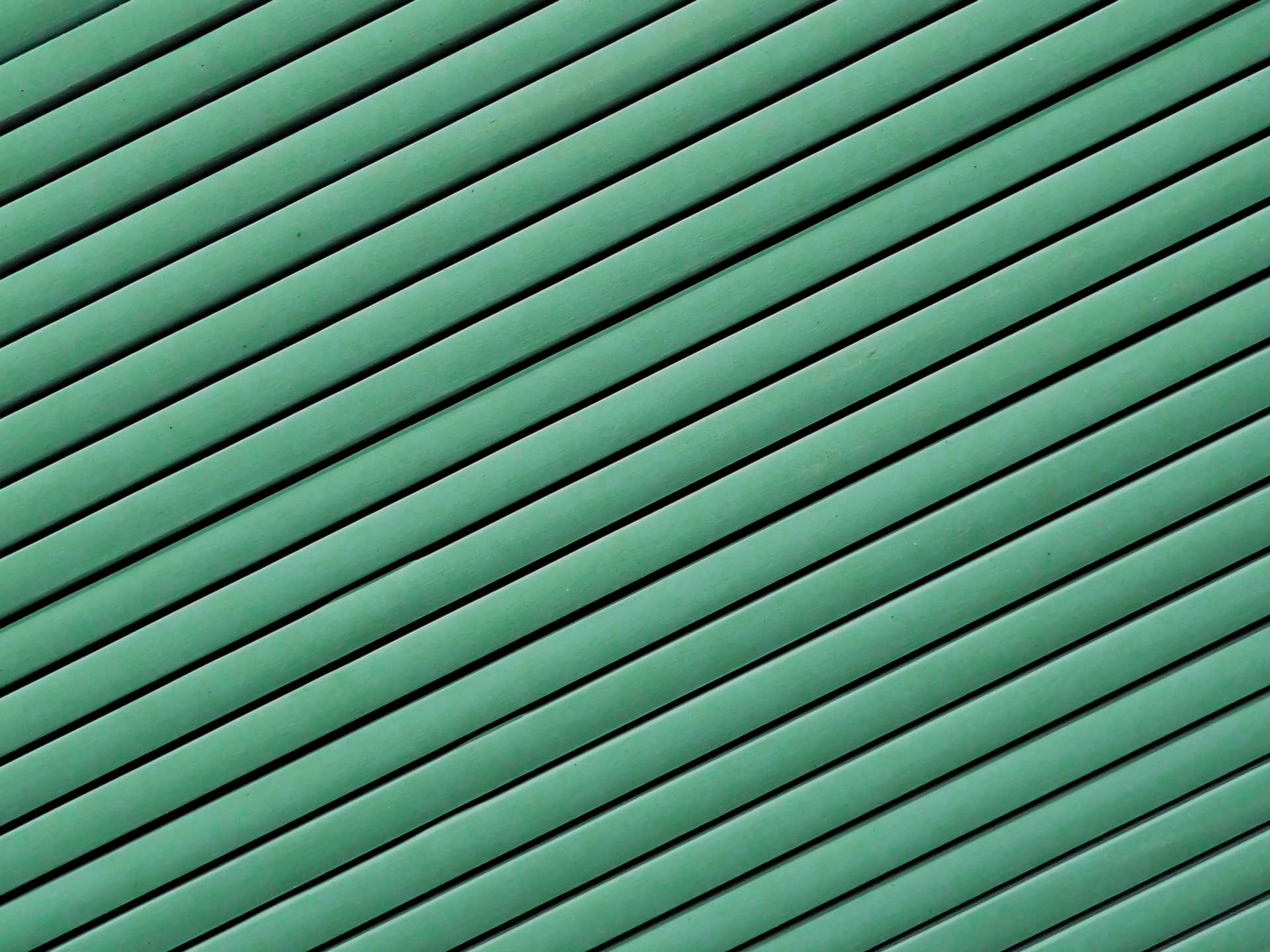 Ein diagonales Muster in verschiedenen Grüntönen, bestehend aus parallelen Linien.