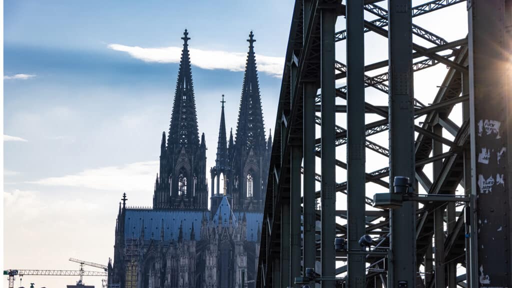 Kölner Dom mit zwei markanten Türmen, sichtbar hinter einer Brücke.