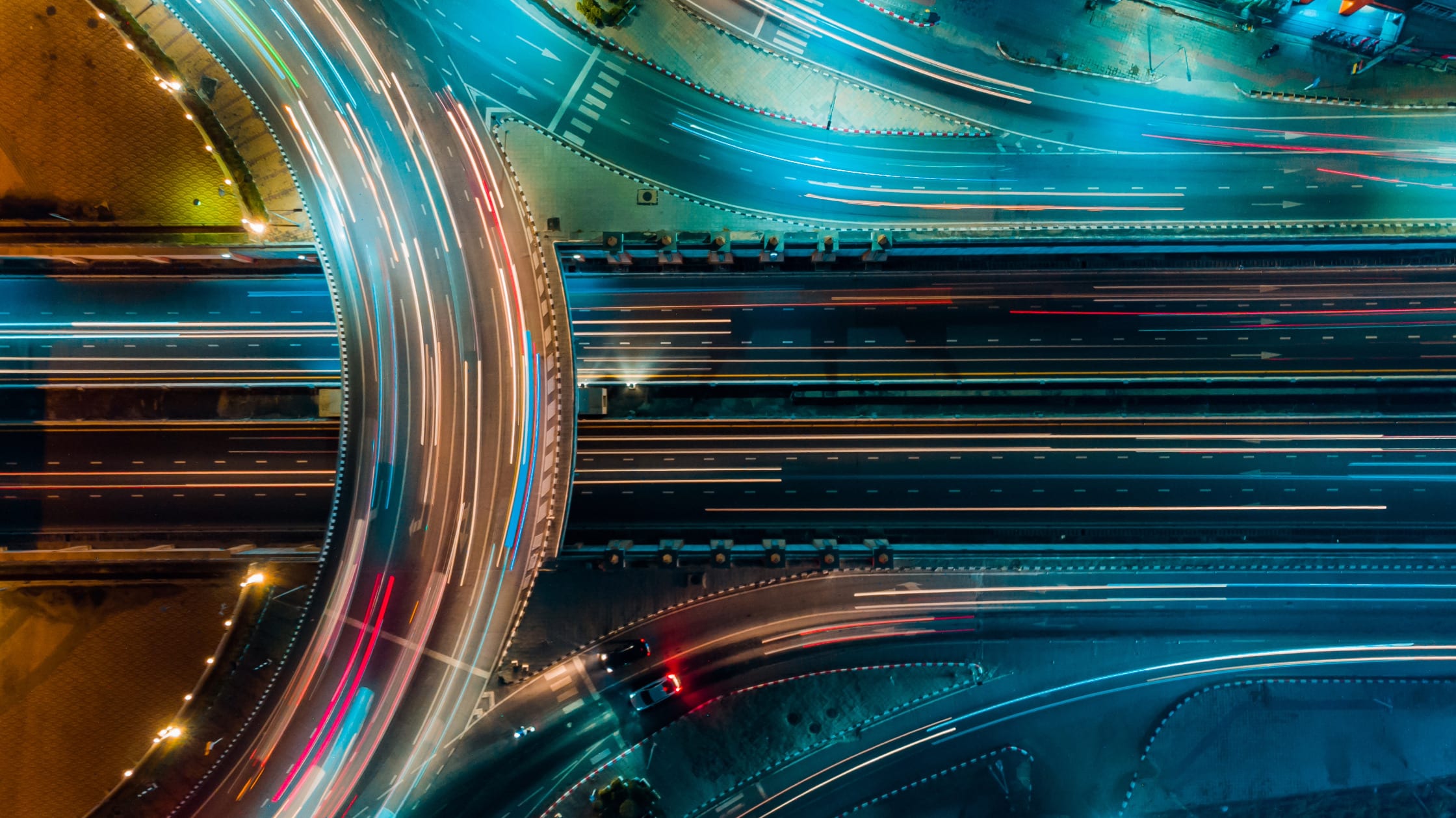 Luftaufnahme einer Straßenkreuzung mit Verkehrslichtern und Fahrzeugen bei Nacht.