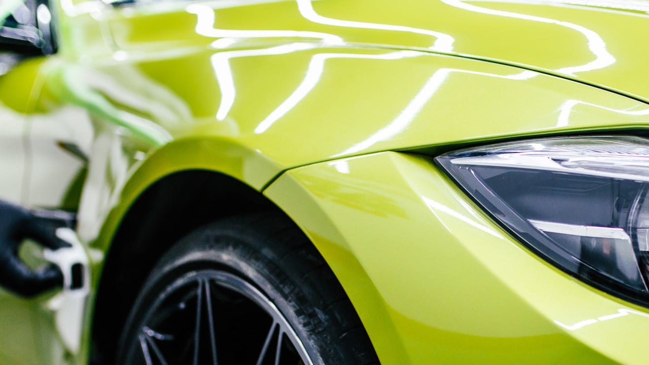 Nahaufnahme eines grünen Autos mit glänzender Lackierung und sportlichem Rad.