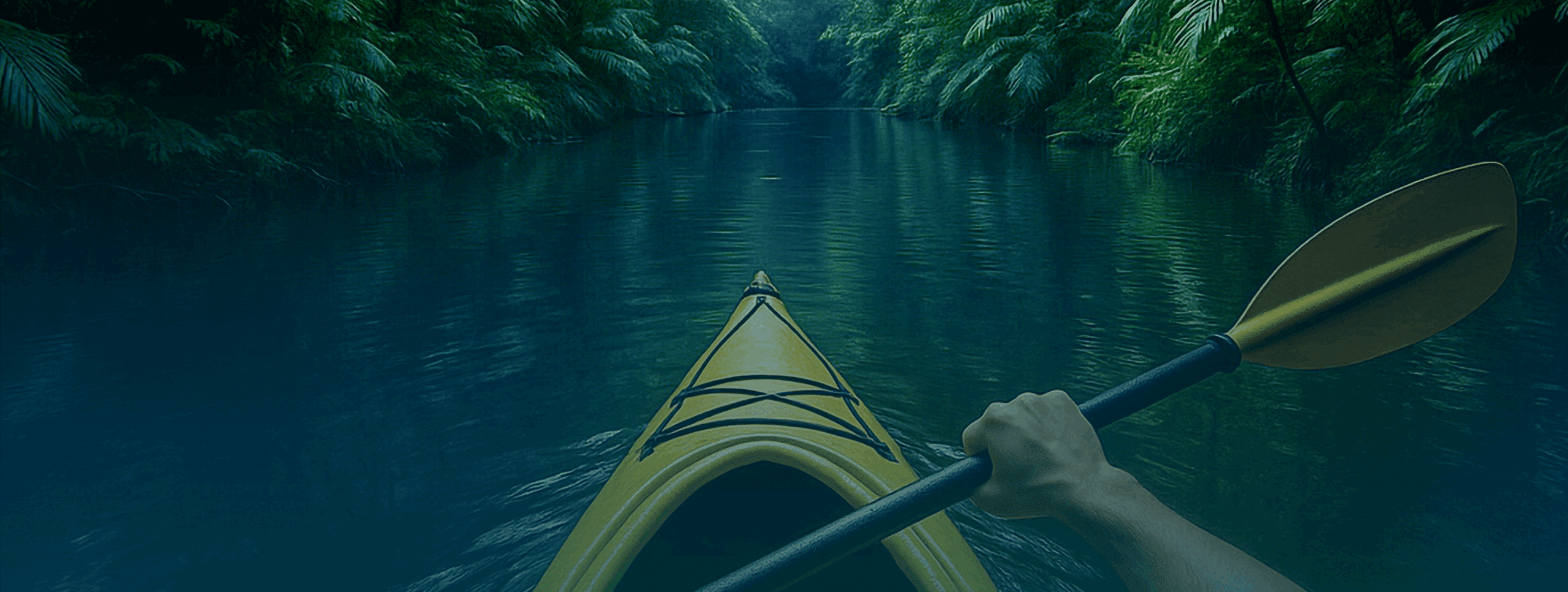 Gelbes Kajak mit Paddel auf ruhigem Wasser in einer bewaldeten Umgebung.